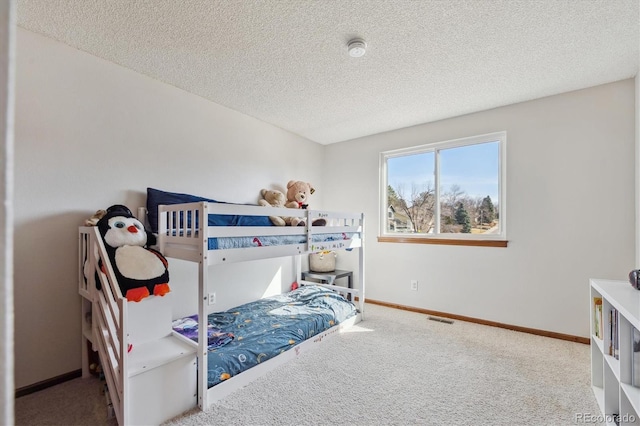 carpeted bedroom with baseboards, visible vents, and a textured ceiling