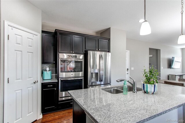 25046 E Bayaud Pl, Aurora, CO 80018 - kitchen with appliances with stainless steel finishes, a sink, light stone counters, and a center island with sink