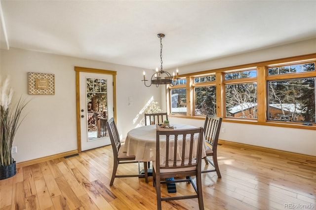 dining space with light wood-type flooring and an inviting chandelier