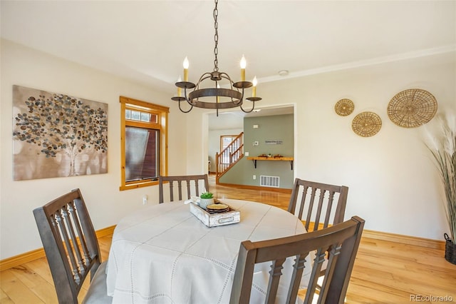 dining area featuring hardwood / wood-style floors, crown molding, and a notable chandelier