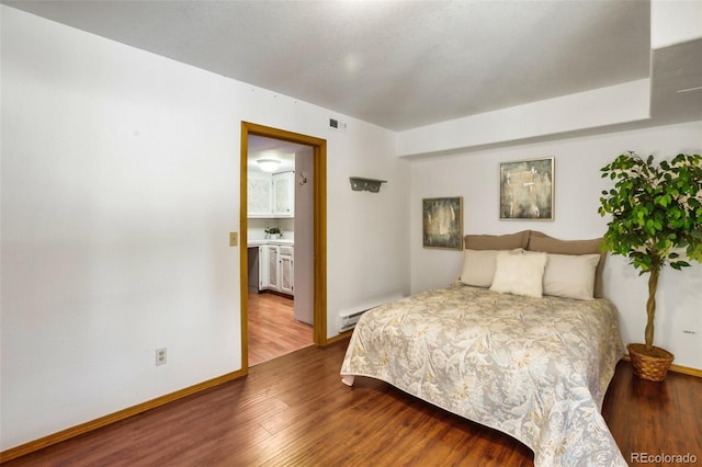 bedroom featuring a baseboard heating unit and hardwood / wood-style flooring