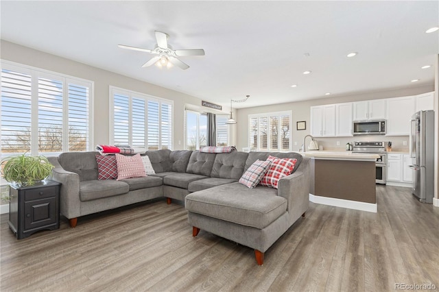 living room featuring ceiling fan, light hardwood / wood-style flooring, a healthy amount of sunlight, and sink