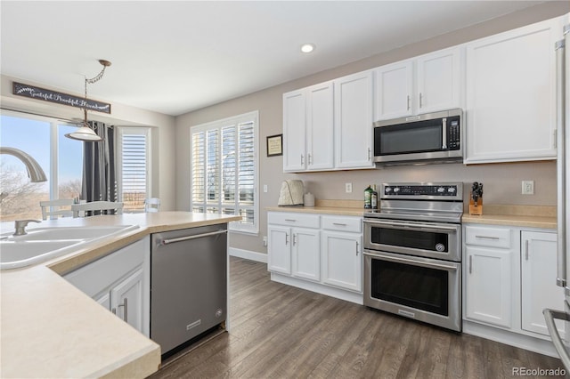 kitchen with white cabinets, appliances with stainless steel finishes, pendant lighting, and sink