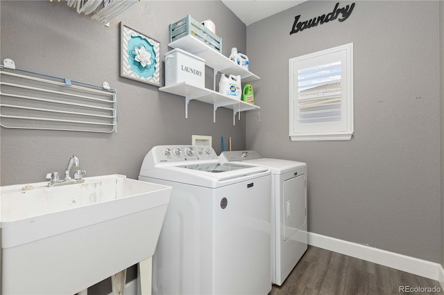 clothes washing area featuring washer and dryer, dark hardwood / wood-style flooring, and sink