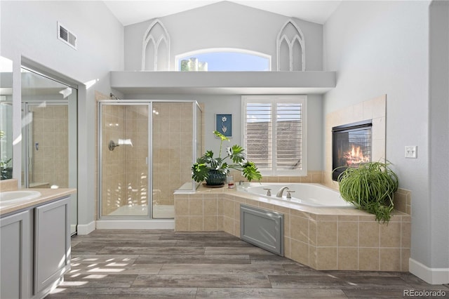 bathroom featuring hardwood / wood-style flooring, vanity, a fireplace, and plus walk in shower