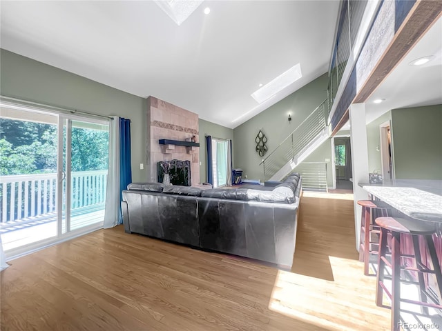 7085 Kiowa Rd, Larkspur, CO 80118 - living room featuring a skylight, wood finished floors, vaulted ceiling, a large fireplace, and stairway