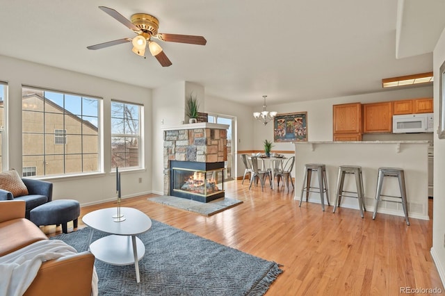 3244 Capstan Way, Colorado Springs, CO 80906 - living room with a fireplace, ceiling fan with notable chandelier, and light hardwood / wood-style flooring