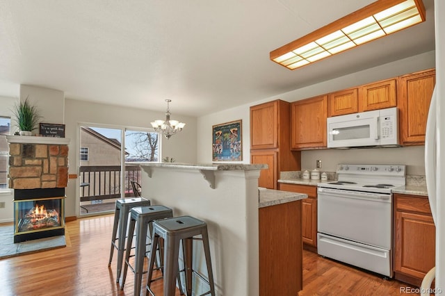 3244 Capstan Way, Colorado Springs, CO 80906 - kitchen featuring a breakfast bar area, a center island, hanging light fixtures, light wood-type flooring, and white appliances