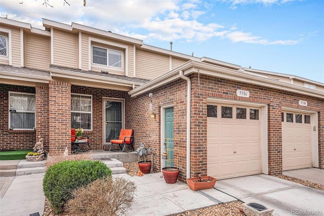 multi unit property with concrete driveway, brick siding, and a garage