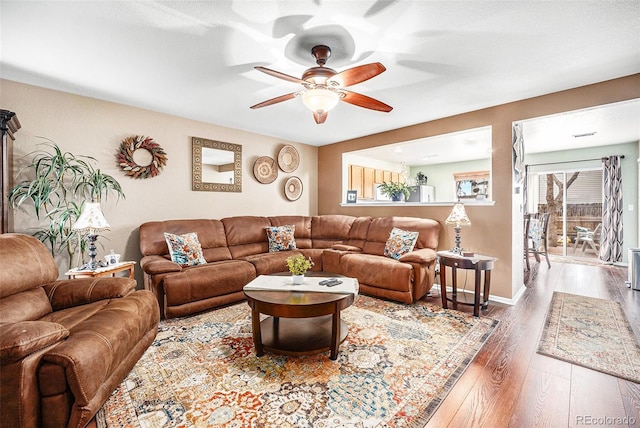 living area with baseboards, wood finished floors, ceiling fan, and a healthy amount of sunlight