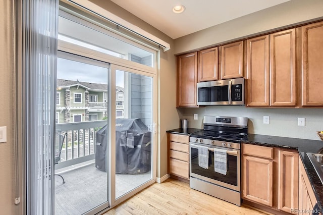 9381 Ashbury Cir Unit 105, Parker, CO 80134 - kitchen with stainless steel appliances, light wood-style floors, brown cabinetry, recessed lighting, and dark stone counters