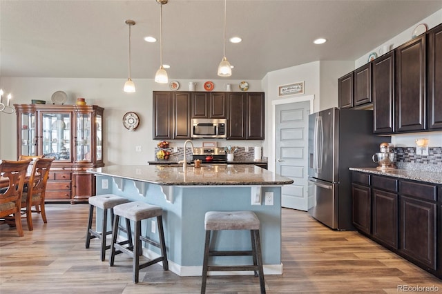 2200 Cadman St, Berthoud, CO 80513 - kitchen featuring appliances with stainless steel finishes, a breakfast bar area, dark brown cabinetry, light wood-style flooring, and recessed lighting