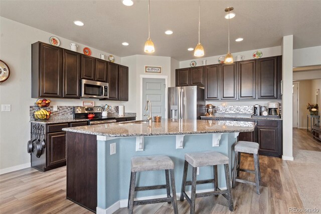 2200 Cadman St, Berthoud, CO 80513 - kitchen featuring appliances with stainless steel finishes, a sink, a breakfast bar area, dark brown cabinets, and recessed lighting
