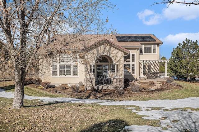 view of front facade featuring a pergola, a front yard, and solar panels