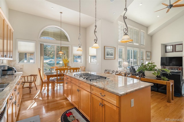 kitchen with ceiling fan, a center island, hanging light fixtures, and high vaulted ceiling