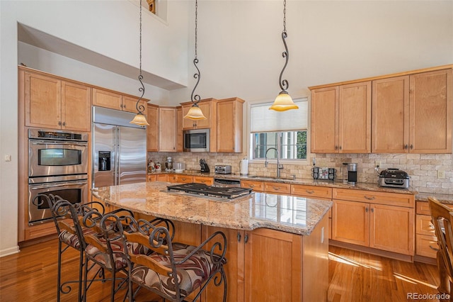 kitchen with sink, a center island, decorative light fixtures, and appliances with stainless steel finishes