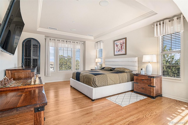 bedroom featuring a tray ceiling and light hardwood / wood-style flooring