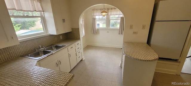 9120 Elm Ct, Denver, CO 80260 - kitchen featuring freestanding refrigerator, a sink, tasteful backsplash, white cabinetry, and light countertops