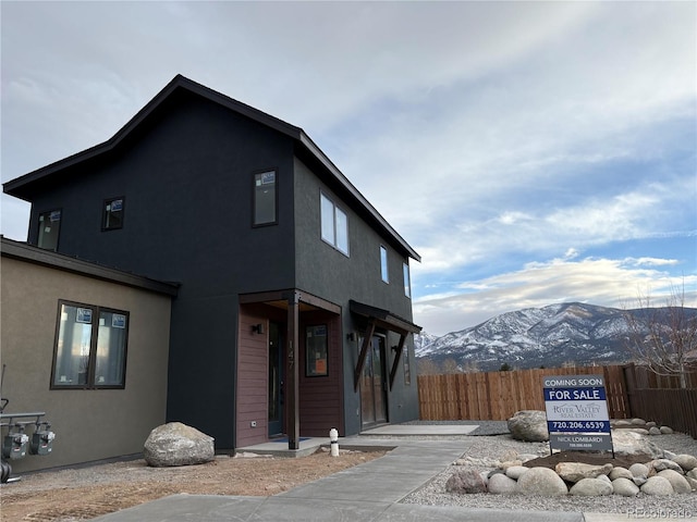 modern home with stucco siding, fence, and a mountain view