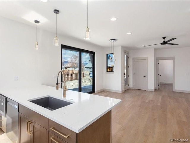 kitchen featuring recessed lighting, a sink, light wood-style floors, stainless steel dishwasher, and pendant lighting