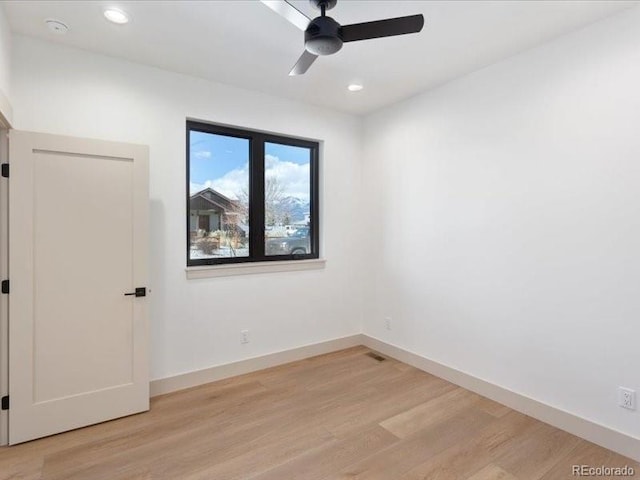 spare room featuring light wood-type flooring, baseboards, and recessed lighting