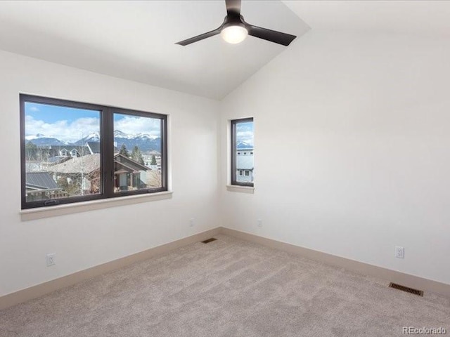 carpeted empty room with lofted ceiling, a ceiling fan, visible vents, and baseboards