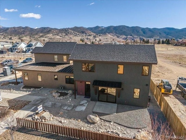 rear view of property with roof with shingles, a patio, a standing seam roof, metal roof, and a mountain view