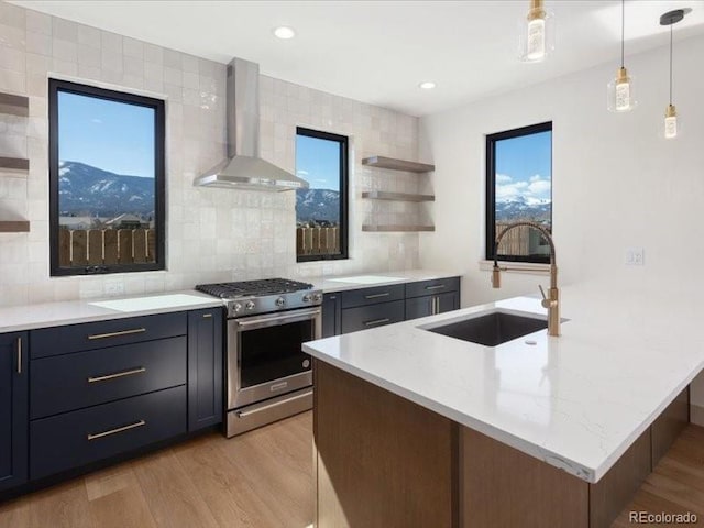 kitchen with open shelves, a sink, light wood-type flooring, stainless steel range with gas cooktop, and wall chimney exhaust hood