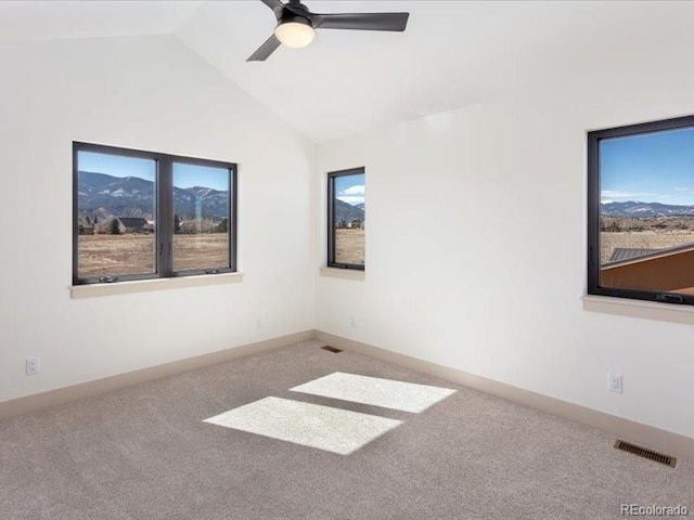 unfurnished room with lofted ceiling, ceiling fan, carpet floors, visible vents, and baseboards