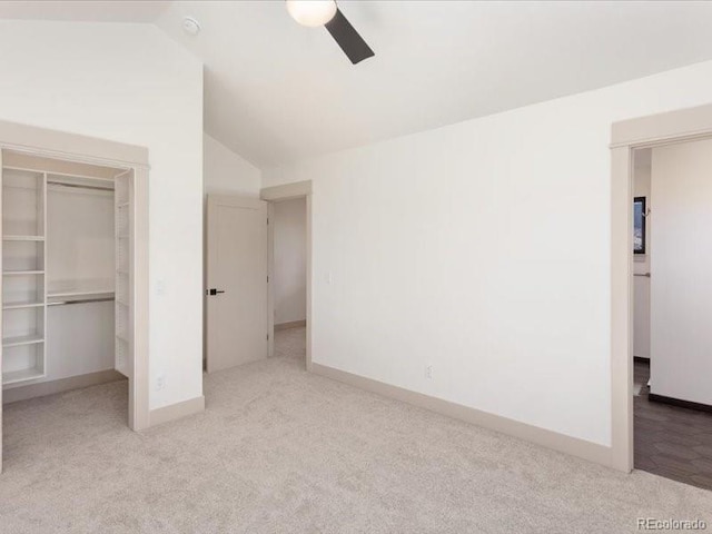 unfurnished bedroom with baseboards, lofted ceiling, a walk in closet, carpet floors, and a closet