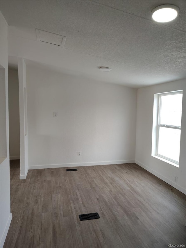 7486 Harold St, Fort Lupton, CO 80621 - spare room featuring dark wood-style flooring, baseboards, attic access, and a textured ceiling