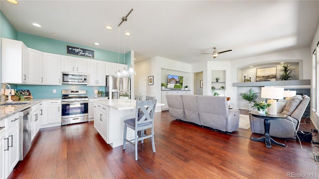 kitchen featuring appliances with stainless steel finishes, open floor plan, white cabinets, a breakfast bar, and recessed lighting