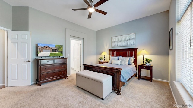 bedroom featuring light colored carpet, baseboards, a ceiling fan, and ensuite bathroom