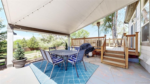 view of patio with outdoor dining area, fence, and a wooden deck