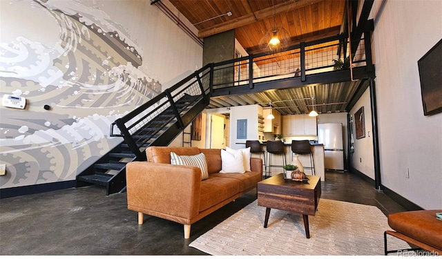 living room featuring electric panel, wooden ceiling, a towering ceiling, and concrete floors