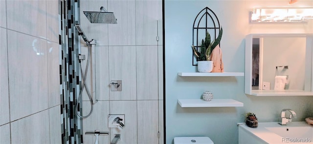 bathroom with toilet, a tile shower, and vanity