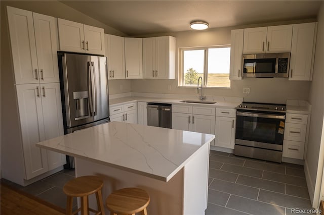 38810 Jacobson Rd, Rush, CO 80833 - kitchen featuring appliances with stainless steel finishes, white cabinets, dark tile patterned flooring, light stone counters, and a kitchen island