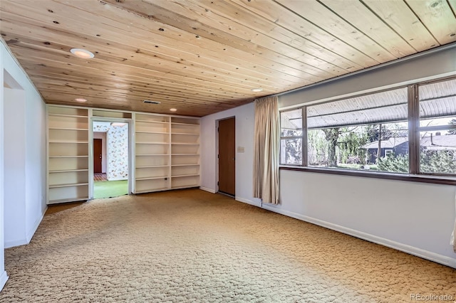 unfurnished room with wood ceiling, built in shelves, baseboards, and carpet floors