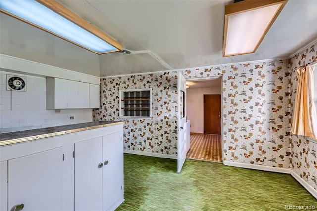 kitchen featuring white cabinets, carpet floors, wallpapered walls, and tile counters