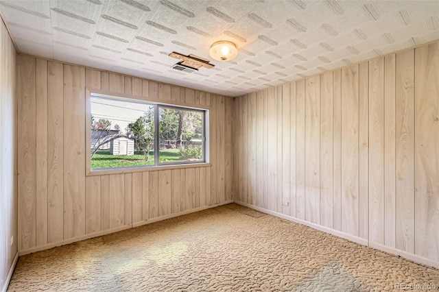 carpeted spare room with wood walls