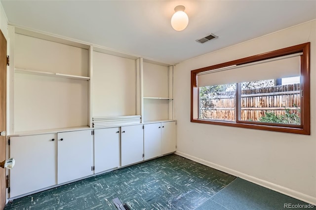spare room featuring dark floors, baseboards, and visible vents