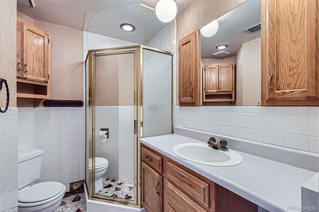 bathroom with toilet, a stall shower, and tile walls