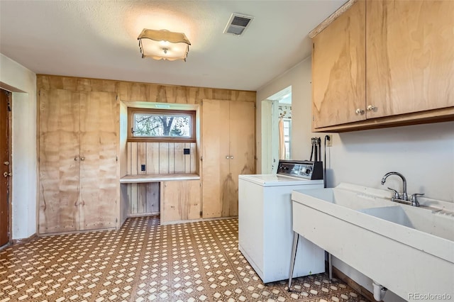washroom featuring light floors, visible vents, a sink, washer / dryer, and cabinet space