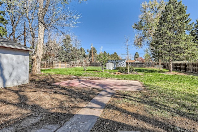 view of yard featuring a storage shed, a fenced backyard, and an outdoor structure
