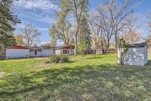 view of yard with a fenced backyard, an outbuilding, and a storage unit