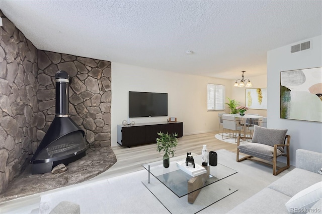 living room with a textured ceiling, a wood stove, and a notable chandelier