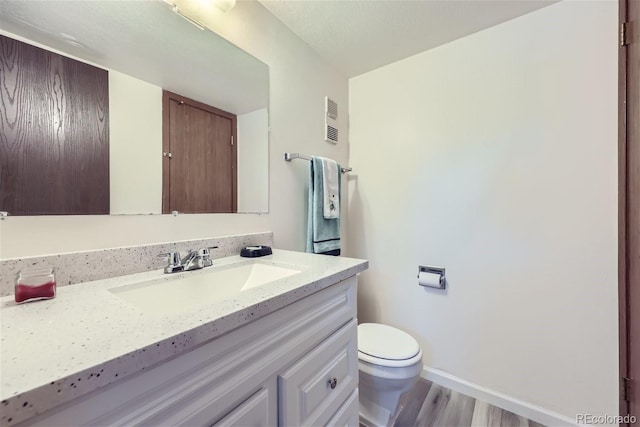 bathroom with toilet, vanity, and hardwood / wood-style flooring