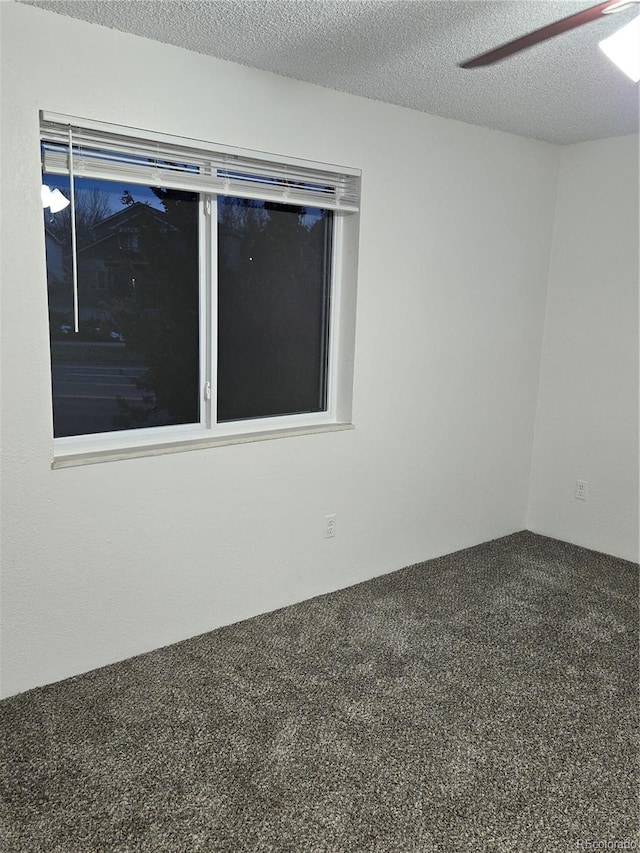 carpeted spare room with a textured ceiling and ceiling fan