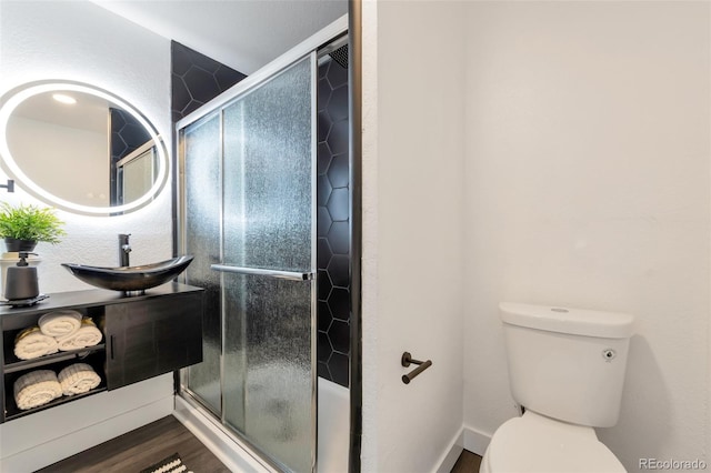 bathroom featuring vanity, toilet, wood-type flooring, and a shower with shower door