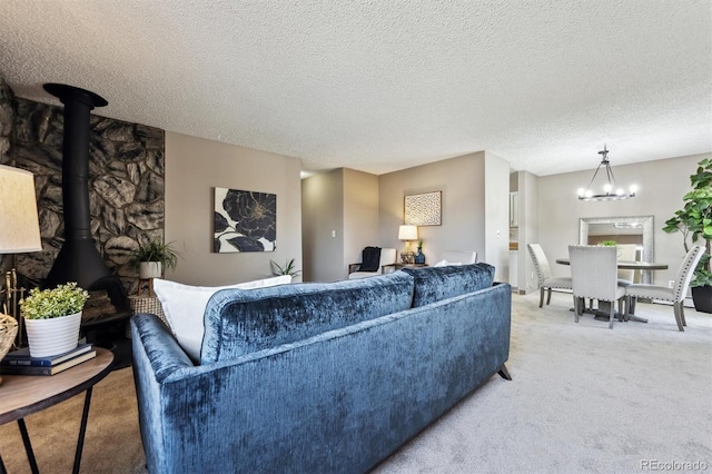 living area with light carpet, a textured ceiling, an inviting chandelier, and a wood stove